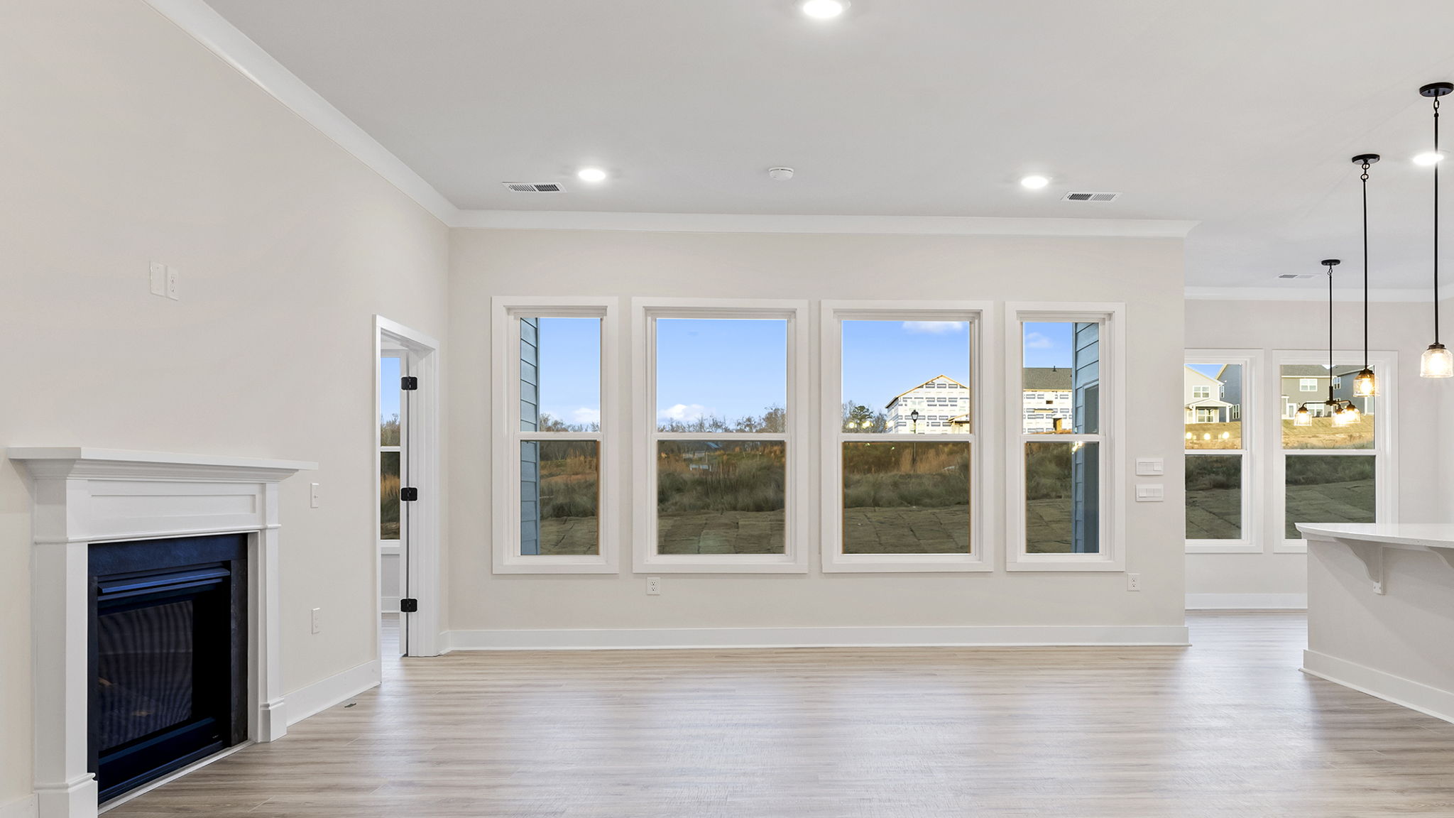 Family room with wall of windows, recessed lighting and gas log fireplace.