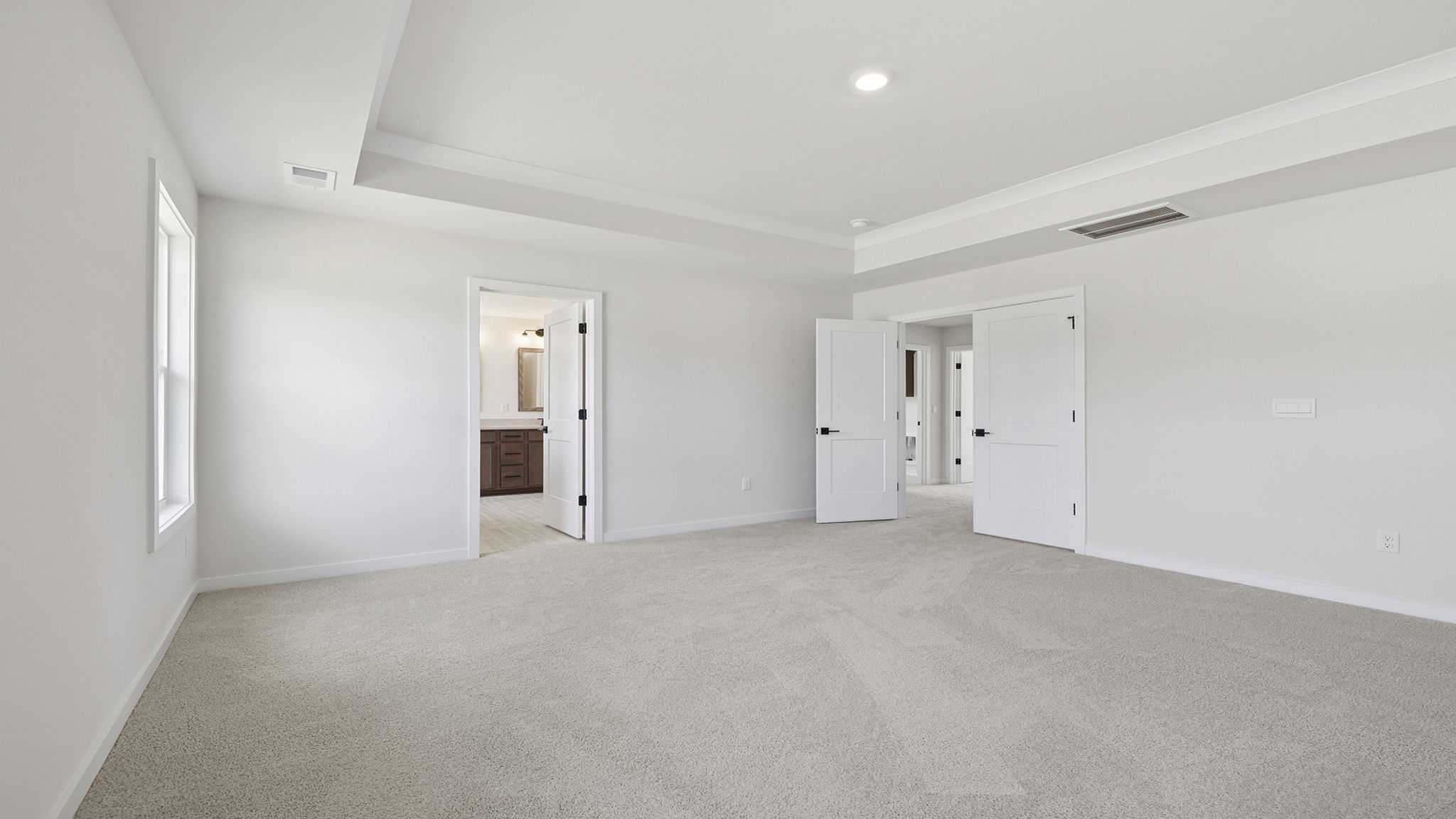 Primary bedroom with trey ceiling, large windows and carpet.