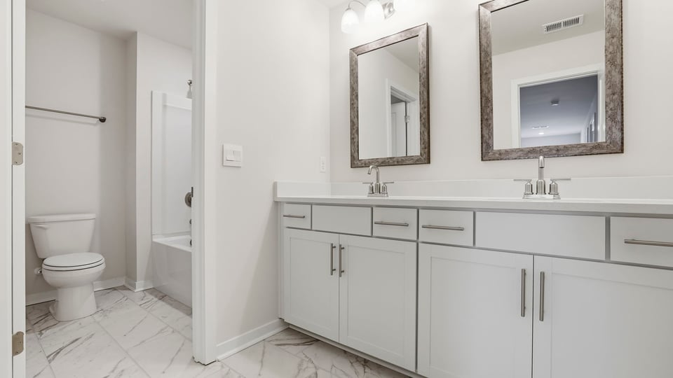 Hall bathroom with dual sink vanity and combination shower / tub.