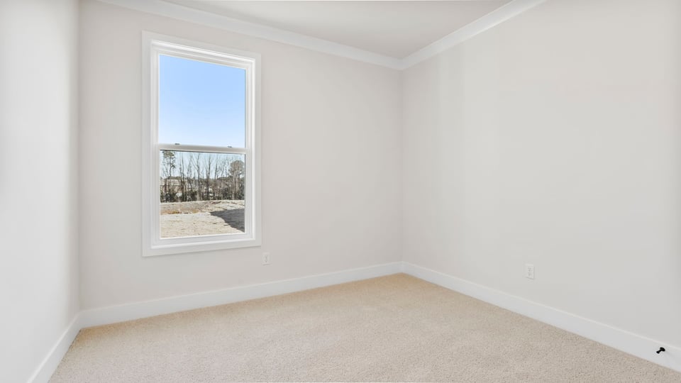Bedroom on the main level with window and carpet.