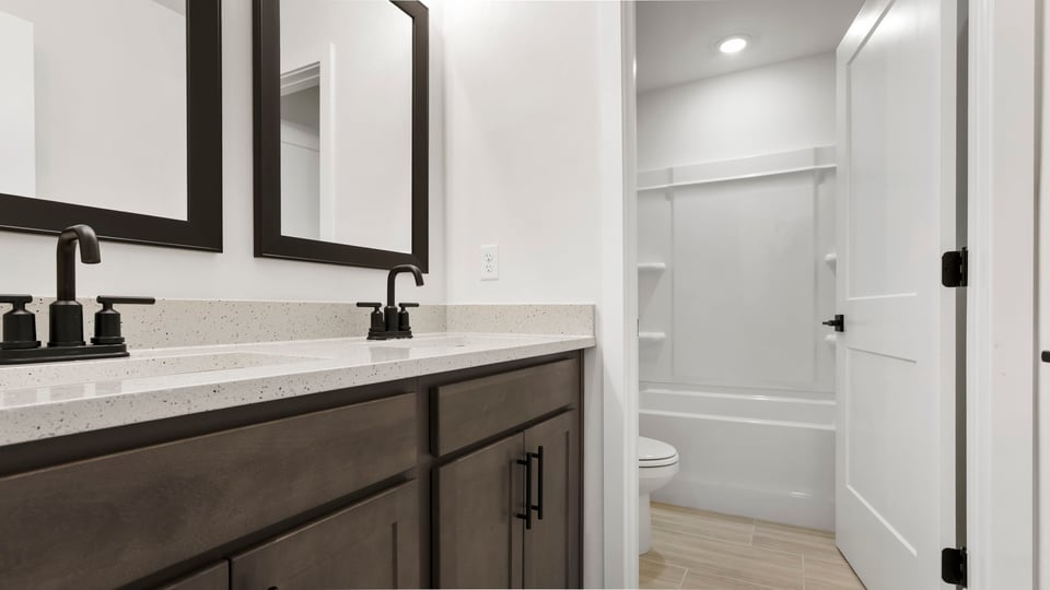 Hall bathroom with dual sink vanity and combination shower / tub.
