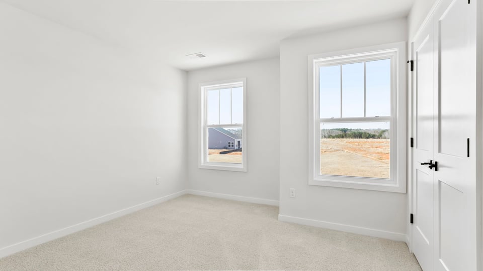 Bedroom with large windows and carpet.