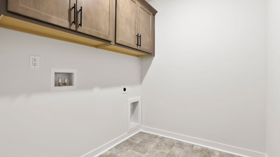 Walk-in laundry room with cabinetry.