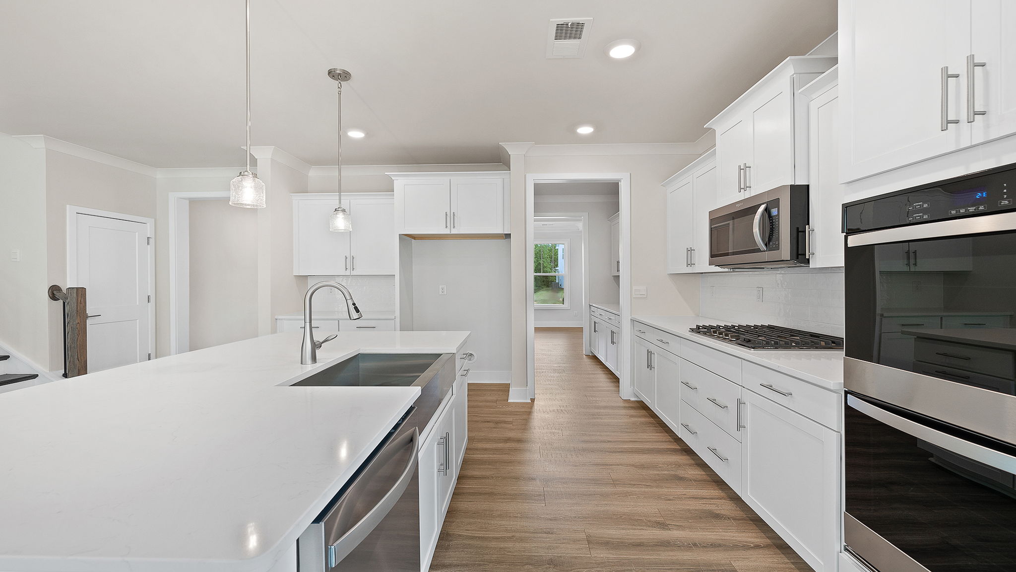 Kitchen and island have quartz countertops, wall ovens and gas cooktop.