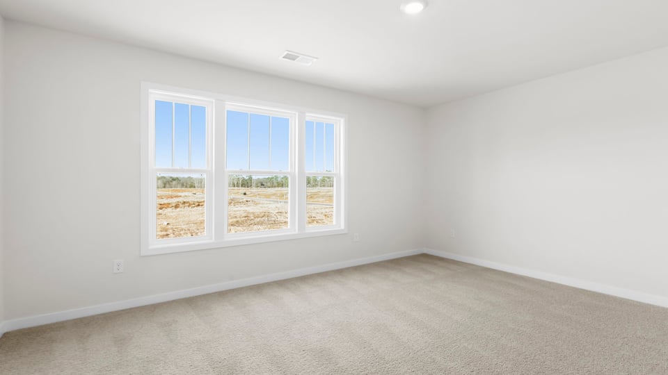 Bedroom with three large windows and carpet.