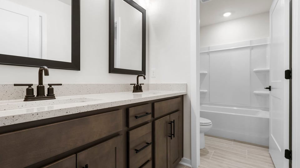 Hall bathroom with dual sink vanity and combination shower / tub.