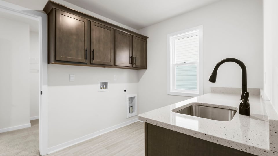 Walk-in laundry room with sink and cabinets.