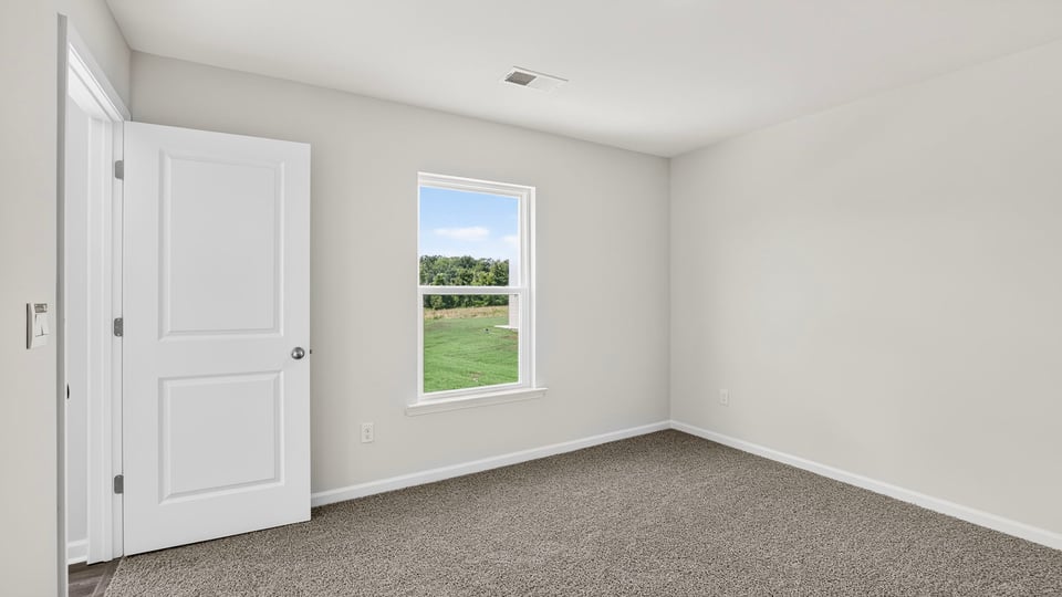 Primary bedroom with carpet and window.