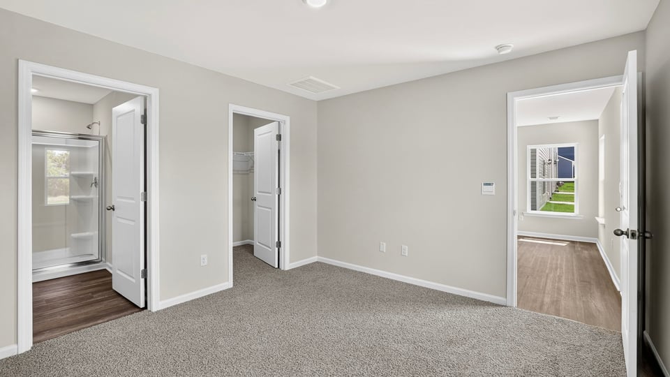 Primary bedroom with carpet and window.