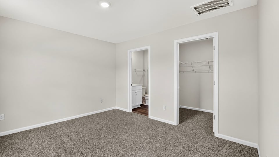 Primary bedroom with carpet and window.