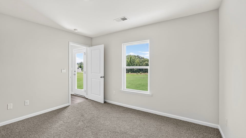 Primary bedroom with carpet and window.