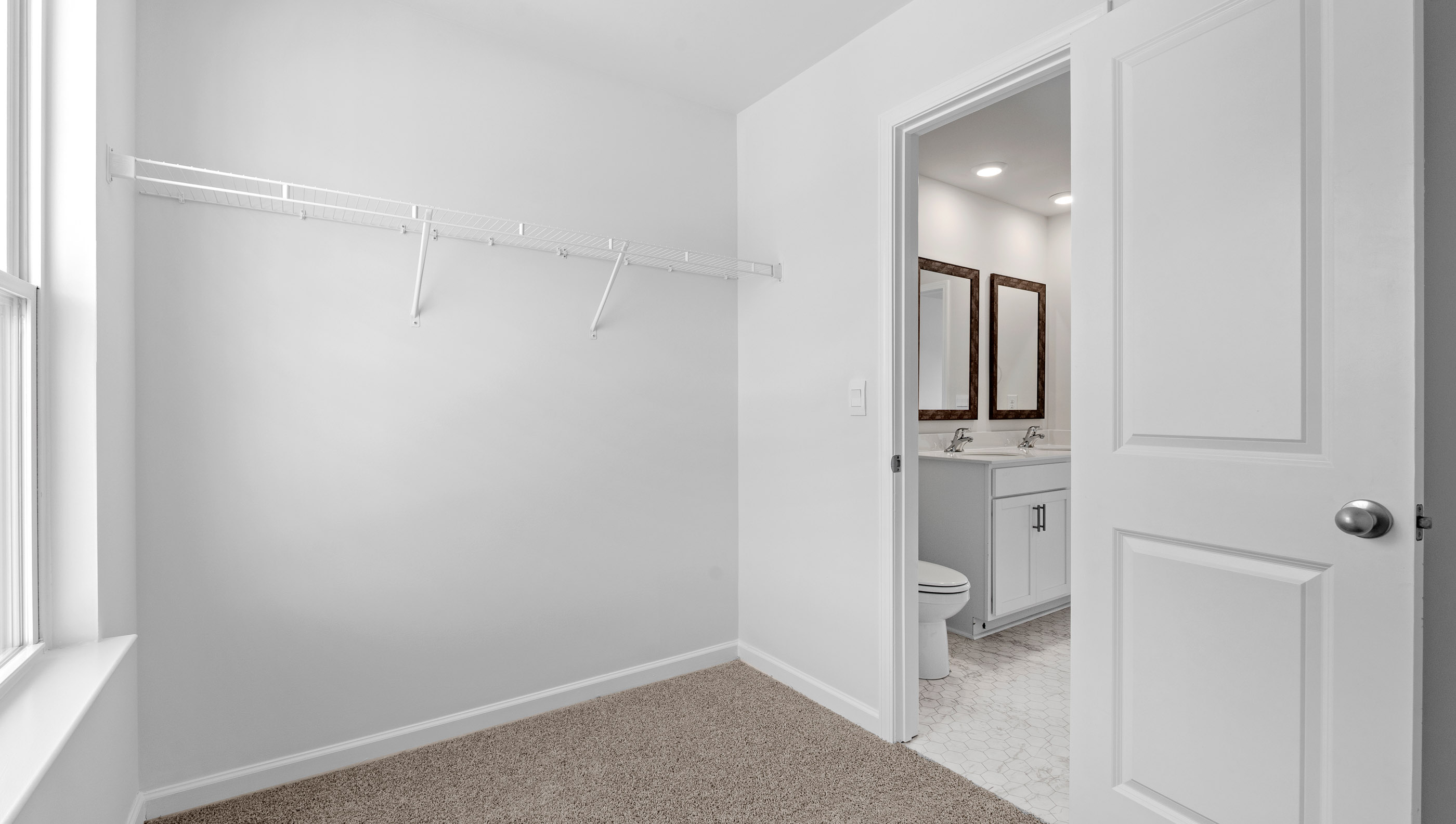 Walk in closet with window and hanging shelves.