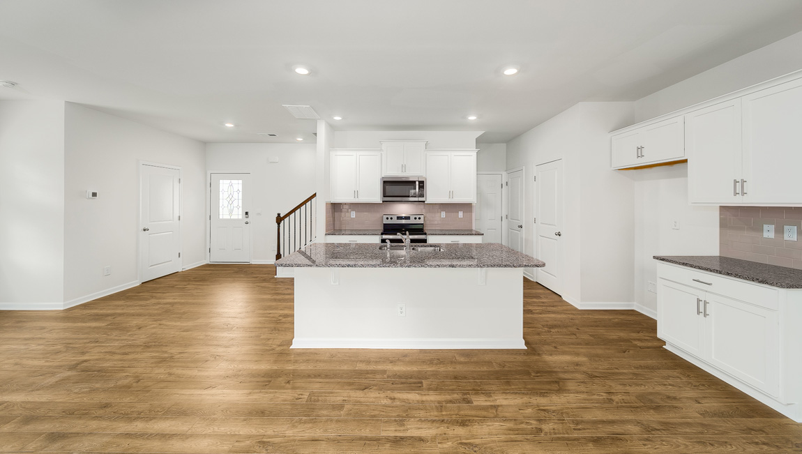 Kitchen and island, white cabinets, vinyl floors, subway tile backsplash and stainless steel appliances