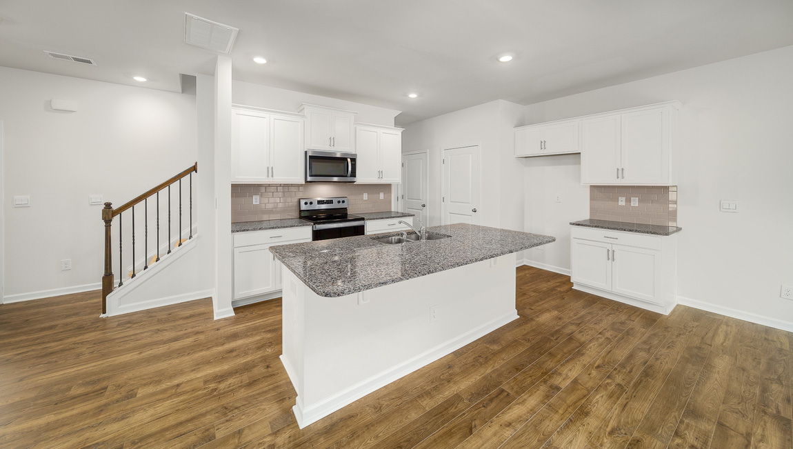 Kitchen and island, white cabinets, vinyl floors, subway tile backsplash and stainless steel appliances