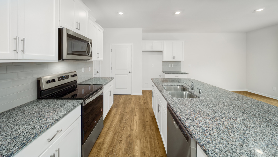 Kitchen and island, white cabinets, vinyl floors, subway tile backsplash and stainless steel appliances