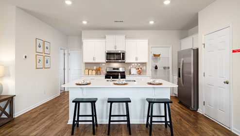 Kitchen and island with white cabinets, subway tile backsplash, and stainless steel appliances