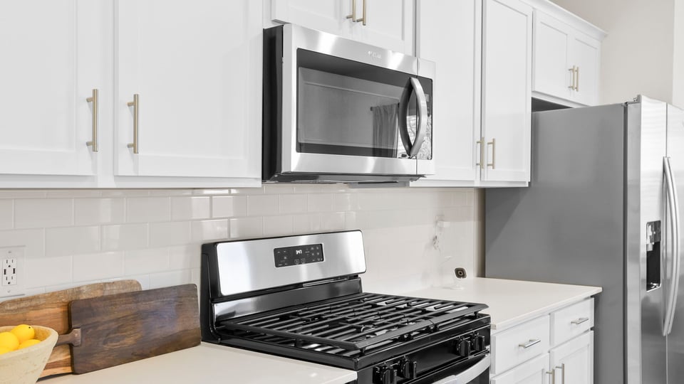 Kitchen and island with quartz and stainless steel appliances.