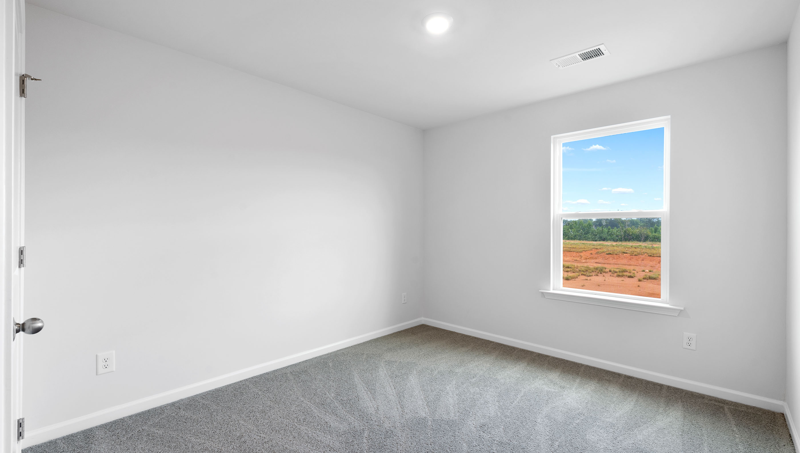 Primary bedroom with carpet and window.