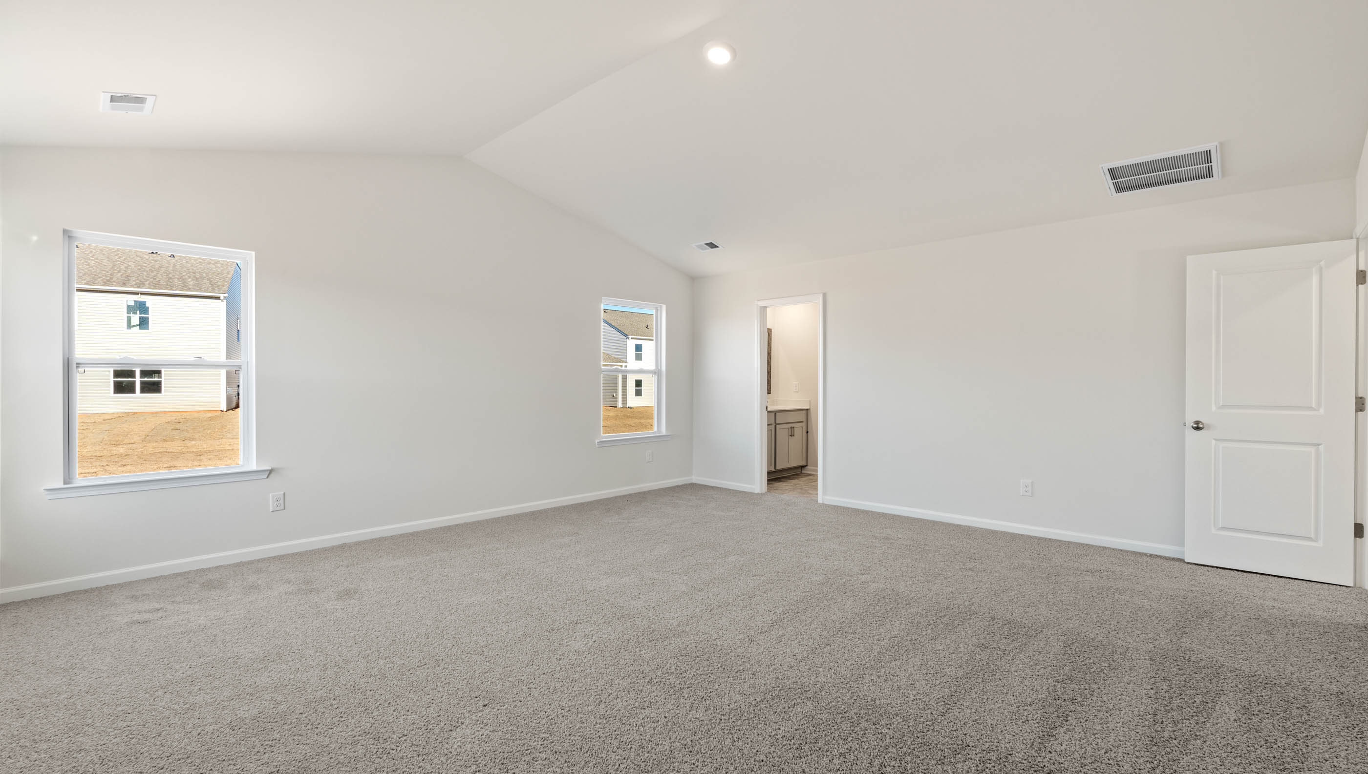 Primary bedroom with carpet and window.