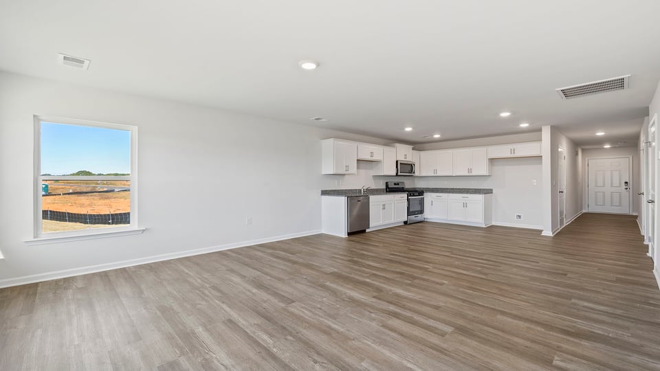 Living room with windows and view of kitchen.