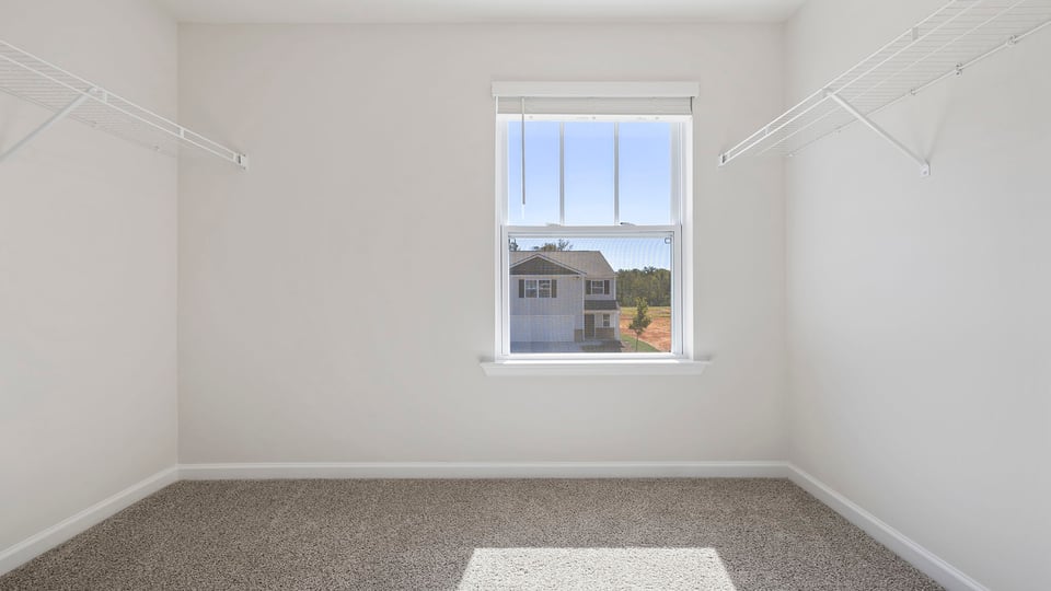 Walk in closet with hanging shelves and a window.