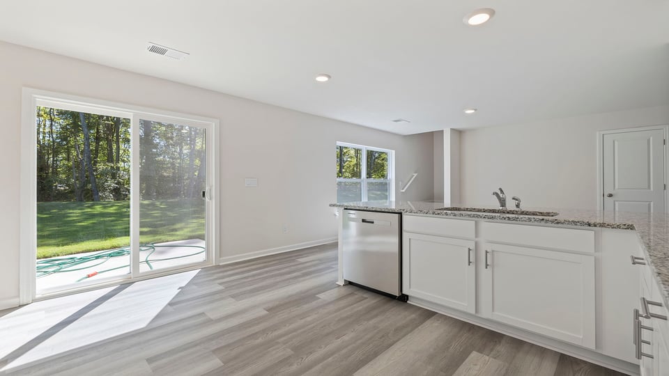 Kitchen with granite countertops and stainless steel appliances facing sliding door.