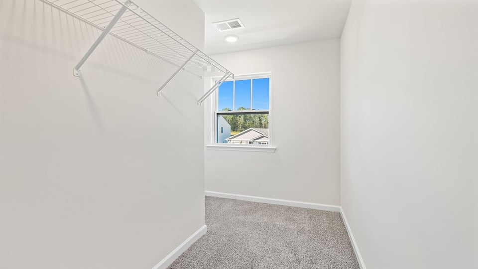 Walk in closet with shelves and window.