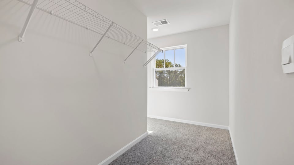 Walk in closet with hanging shelves and window.