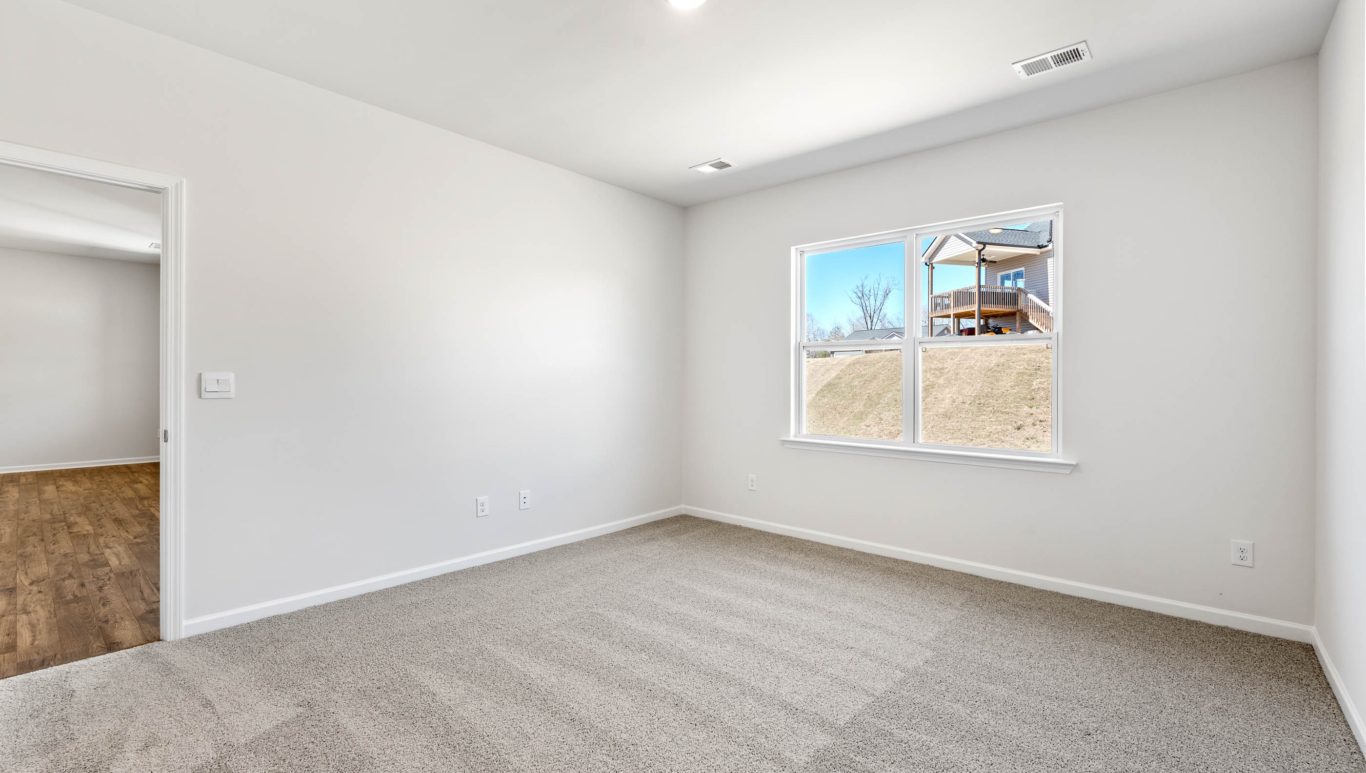 Primary bedroom with carpet and window.
