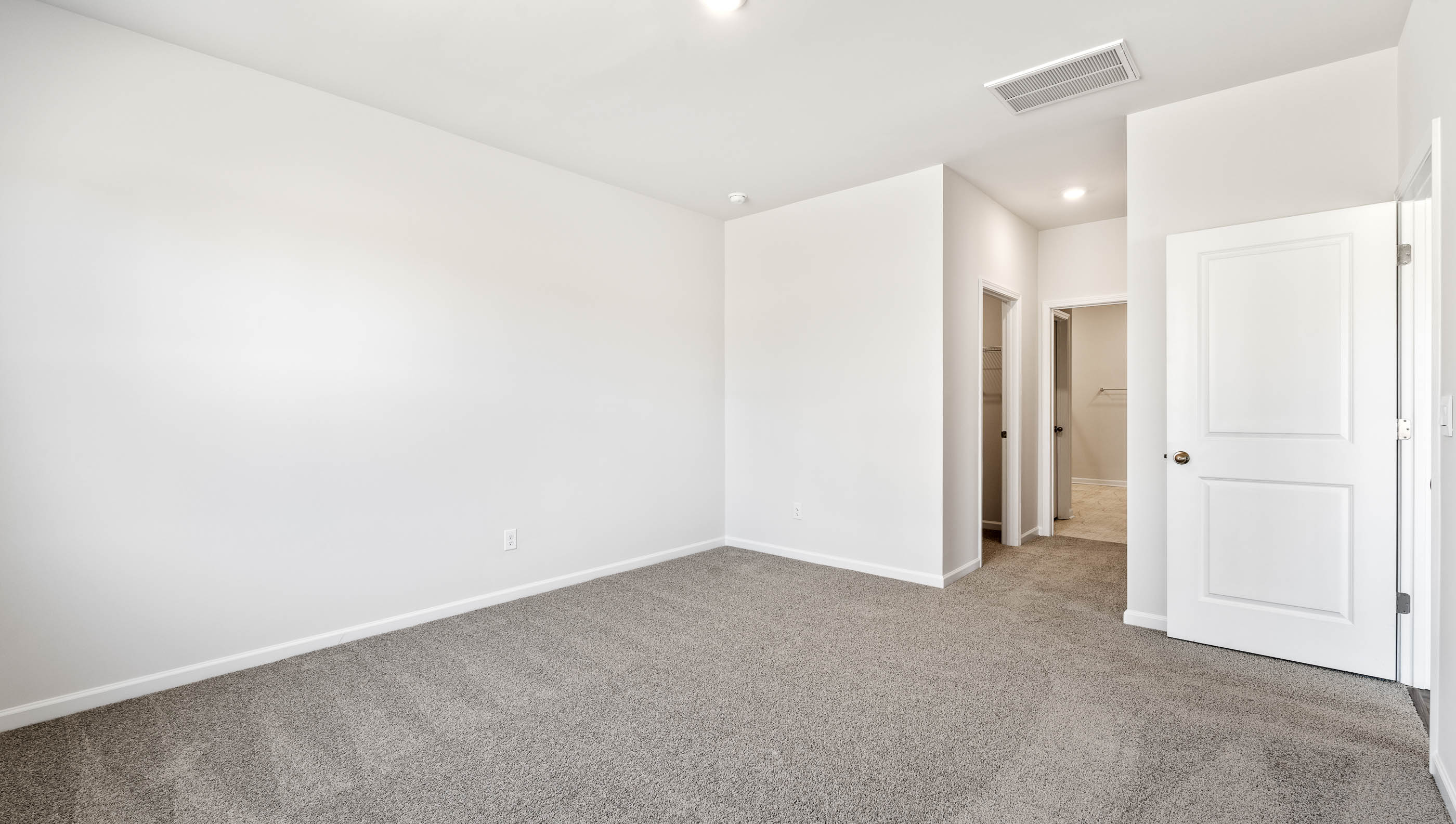 Primary bedroom with carpet and window.