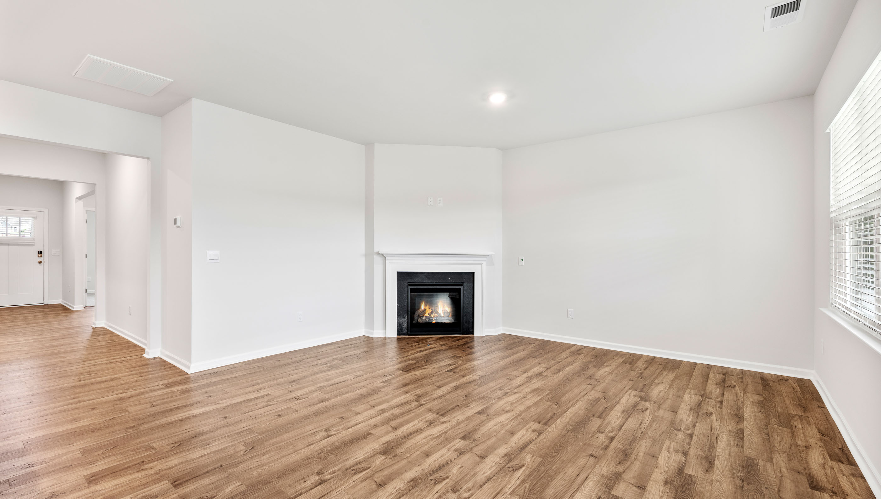 Family room with gas log fireplace and view of hallway to the entry.