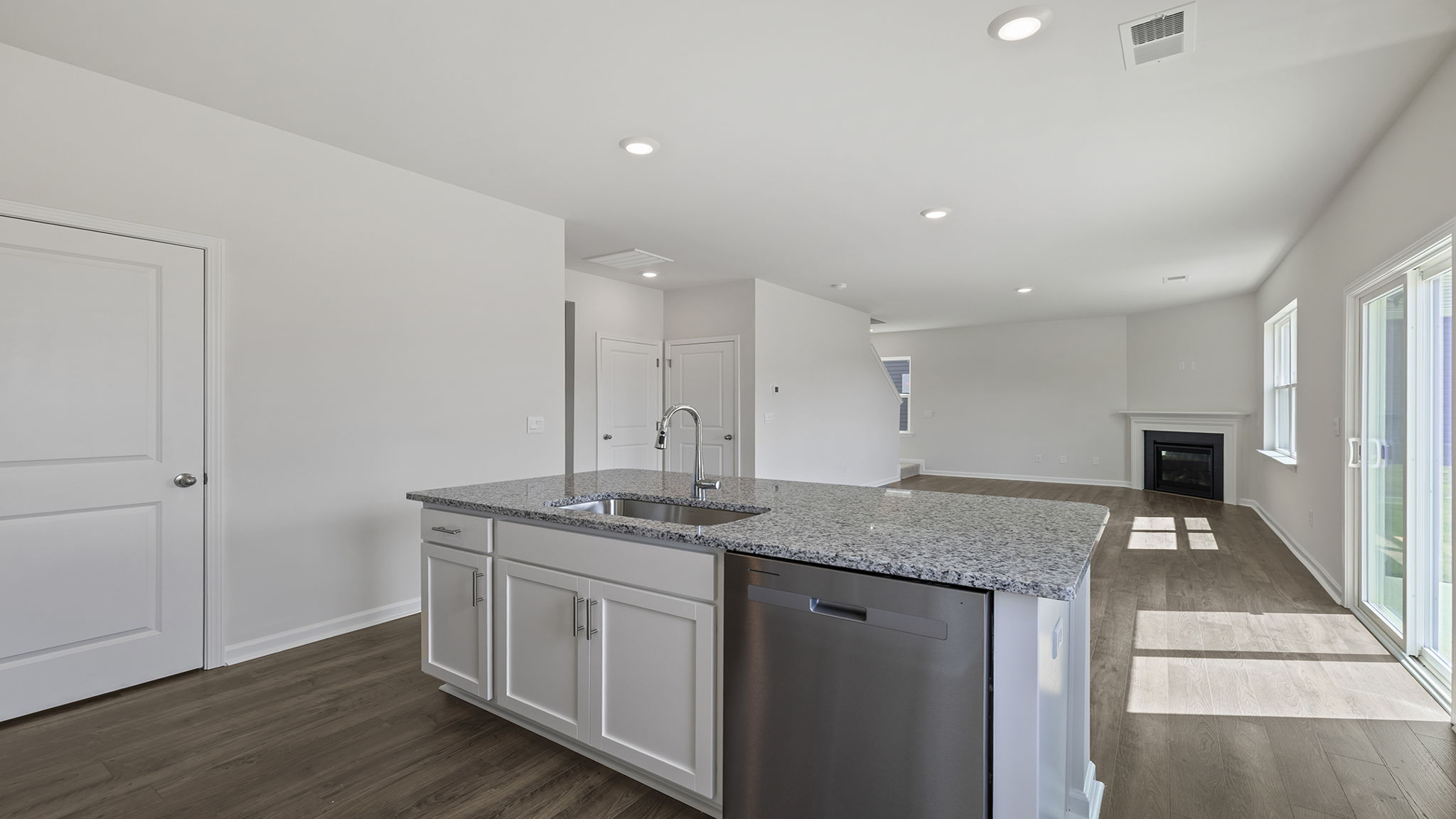 Kitchen with island and view of family room with windows.