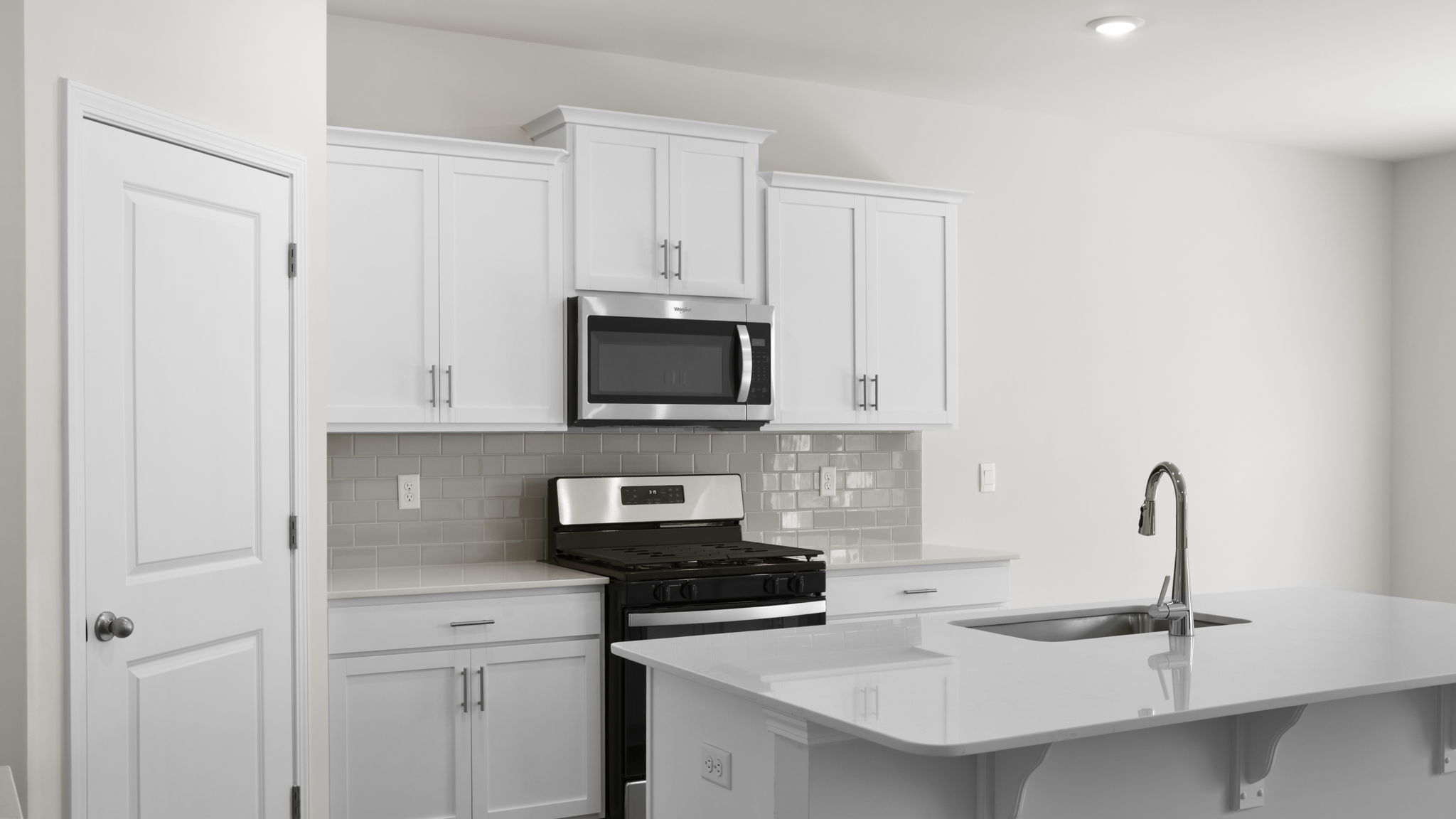 Kitchen and island with quartz countertops and stainless steel appliances.