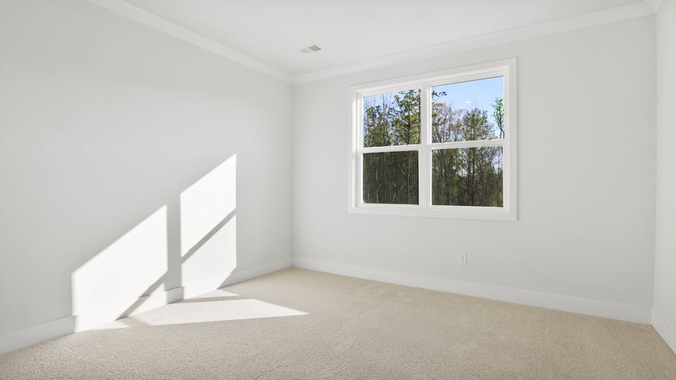 Primary bedroom with carpet and windows.