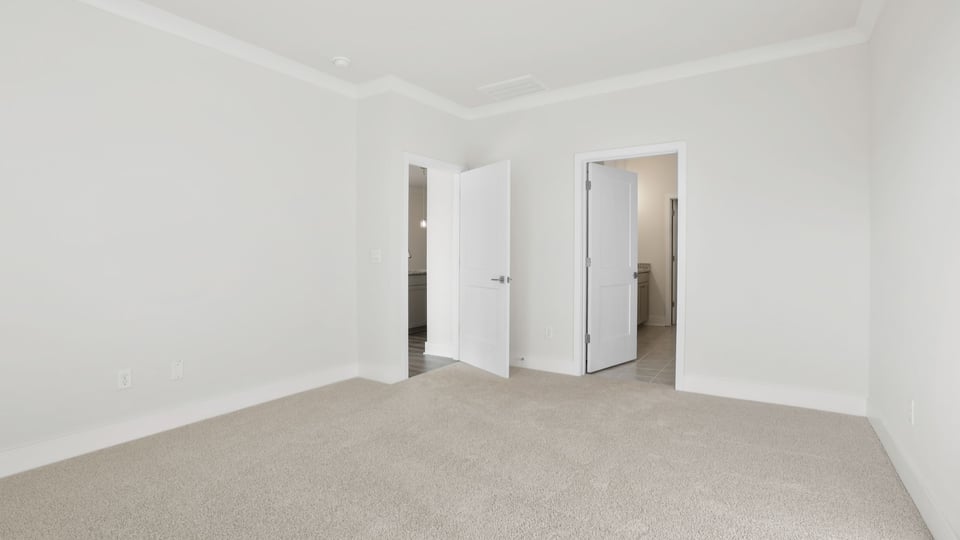 Primary bedroom with carpet and windows.
