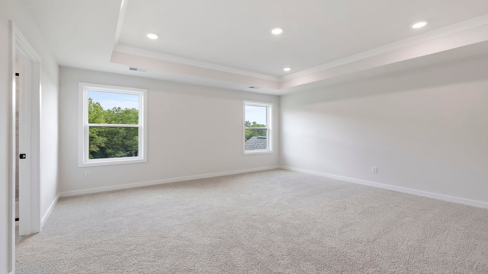 Primary bedroom with carpet and window.