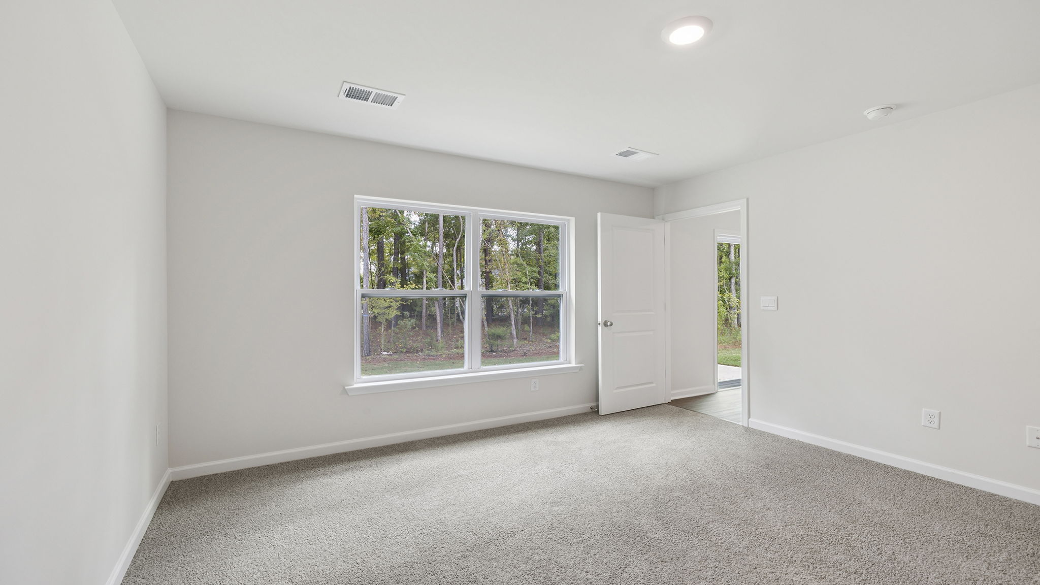 Primary bedroom with large window and carpet.