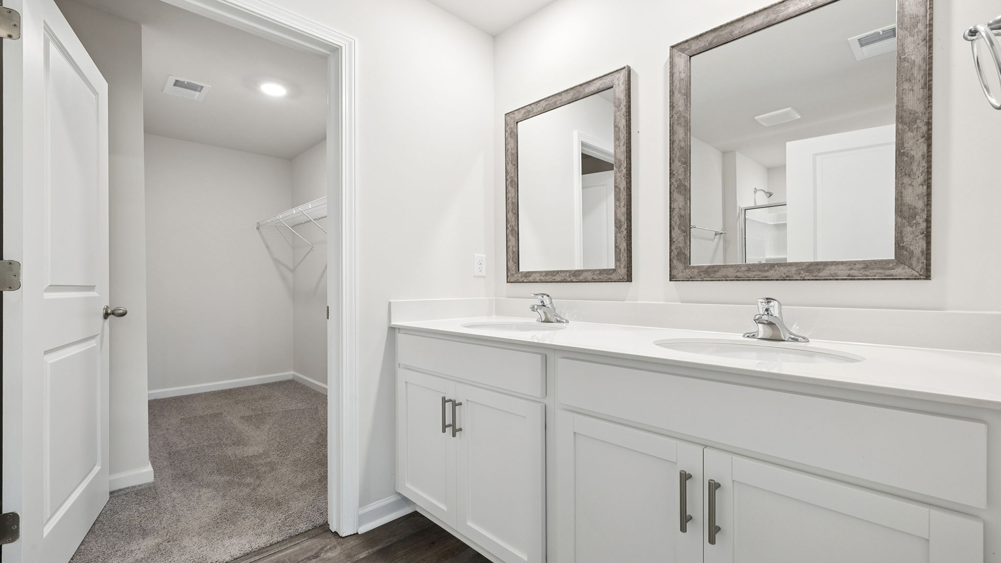 Primary bathroom with dual sink vanity and mirrors.