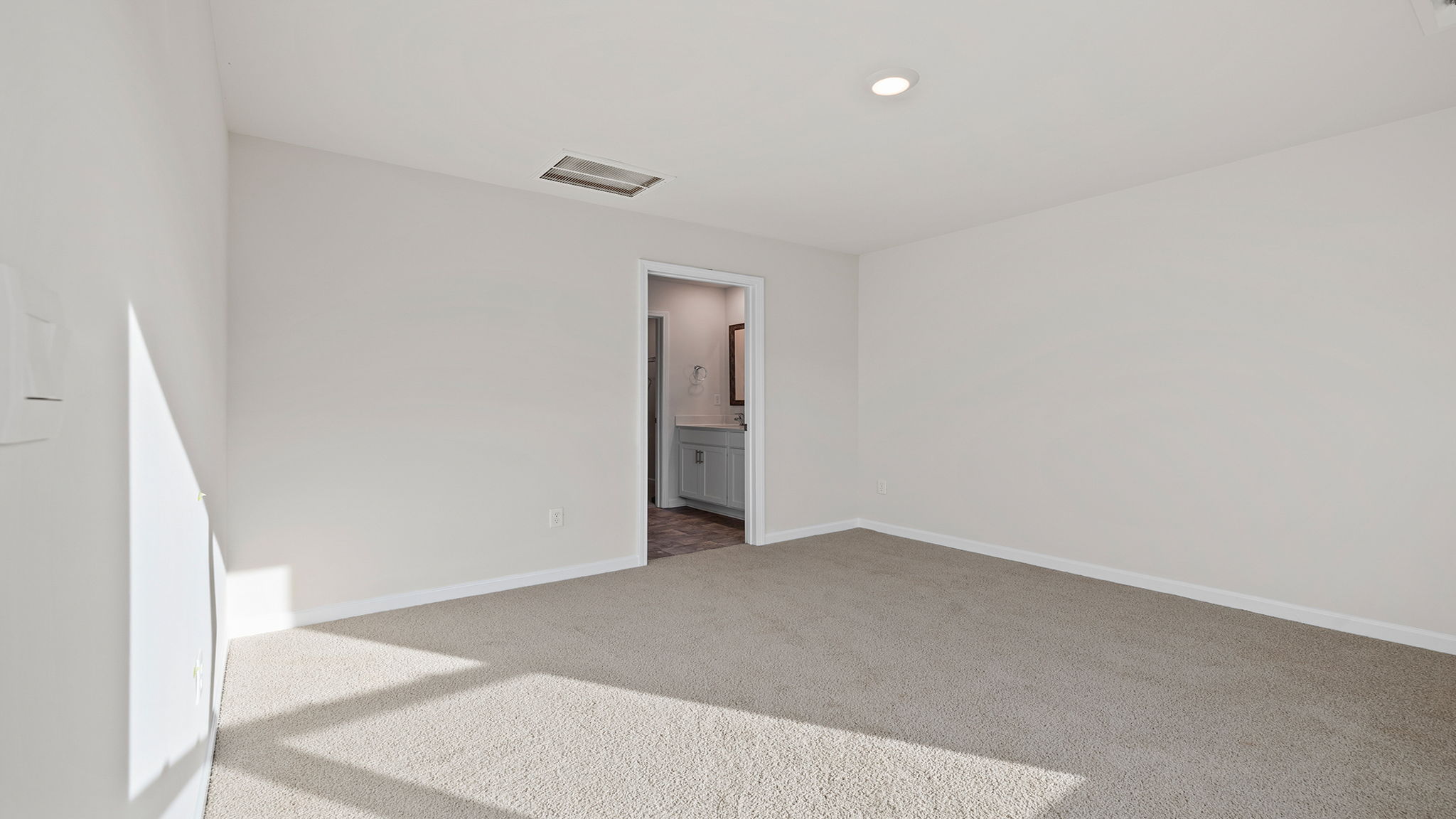 Primary bedroom with carpet and windows.