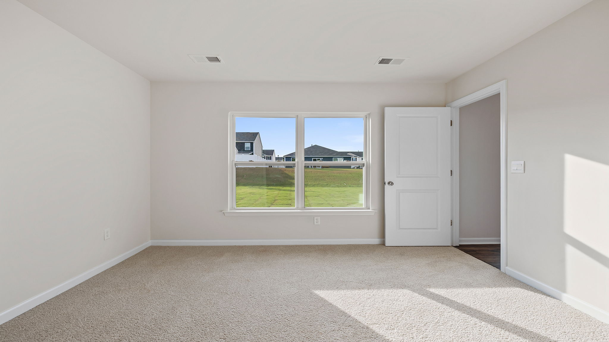 Primary bedroom with carpet and windows.