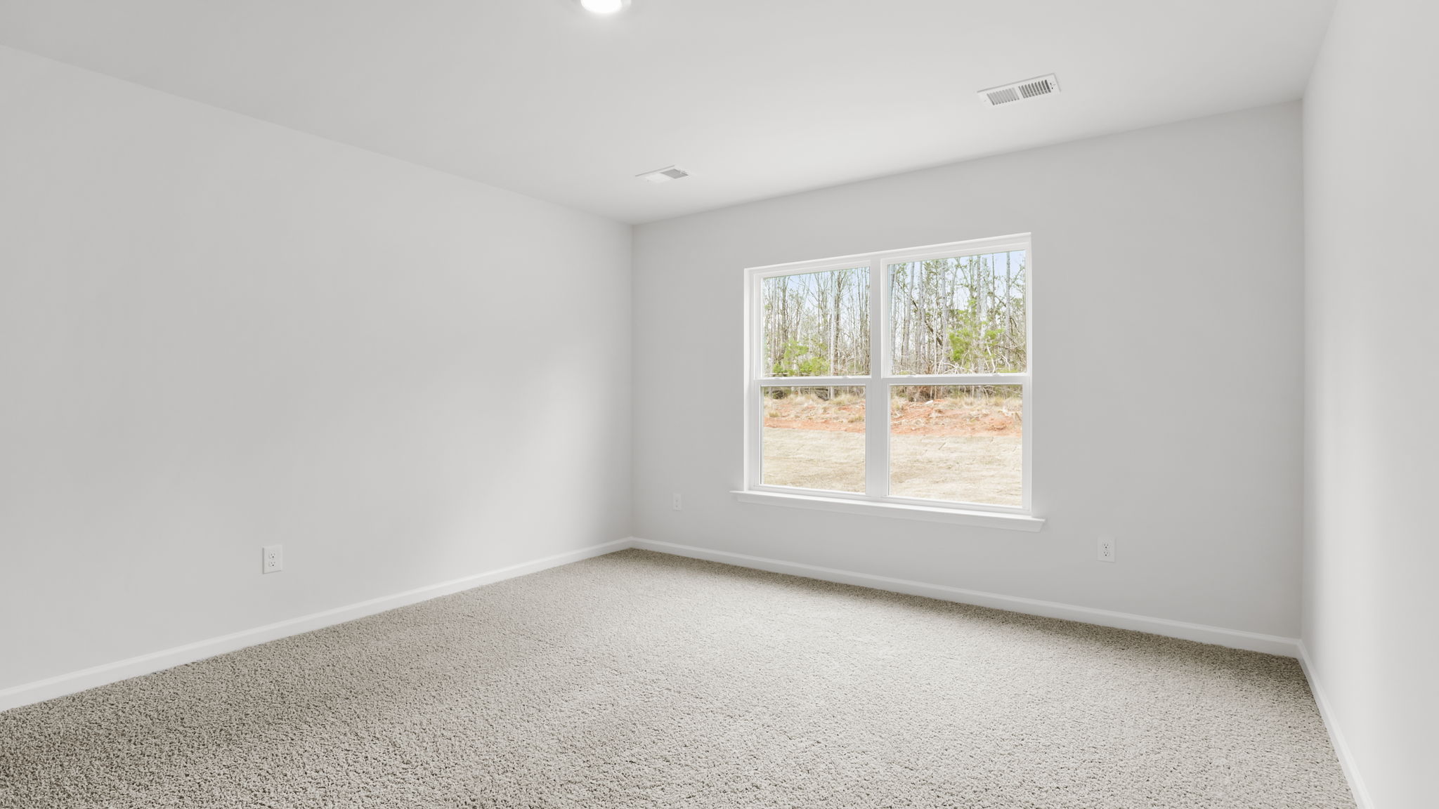 Primary bedroom with carpet and window.