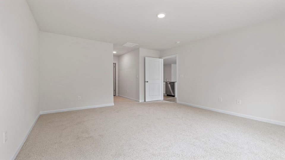 Primary bedroom with carpet and window.