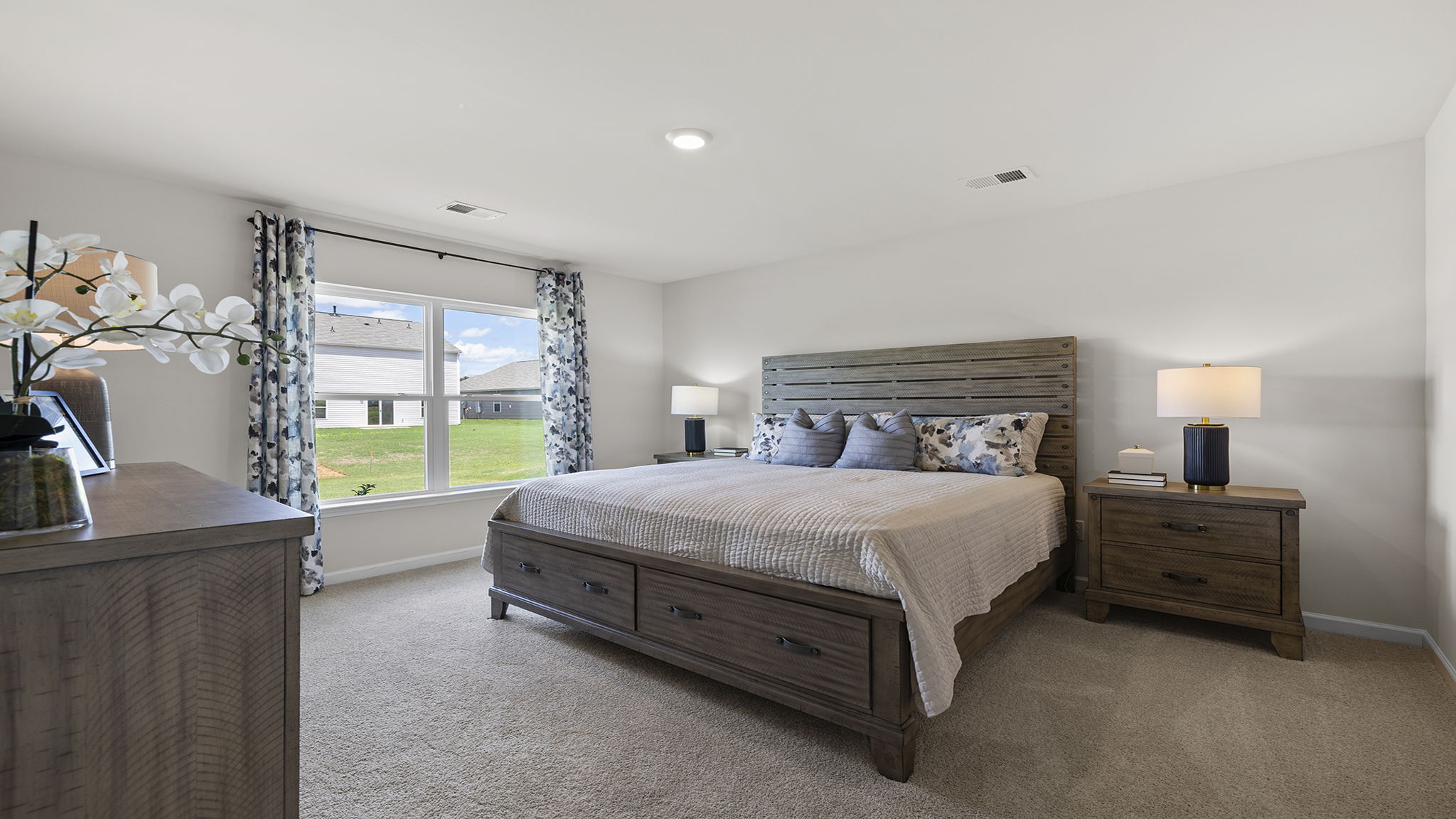 Primary bedroom with carpet and window.