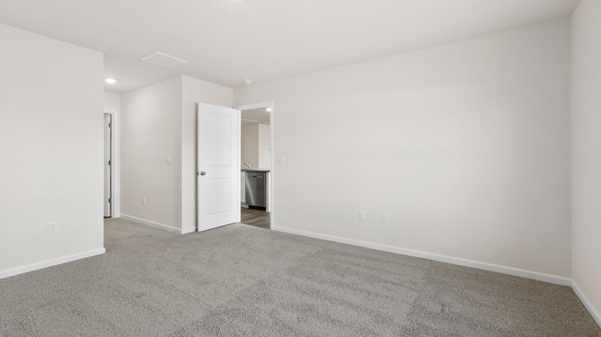 Primary bedroom with carpet and window.