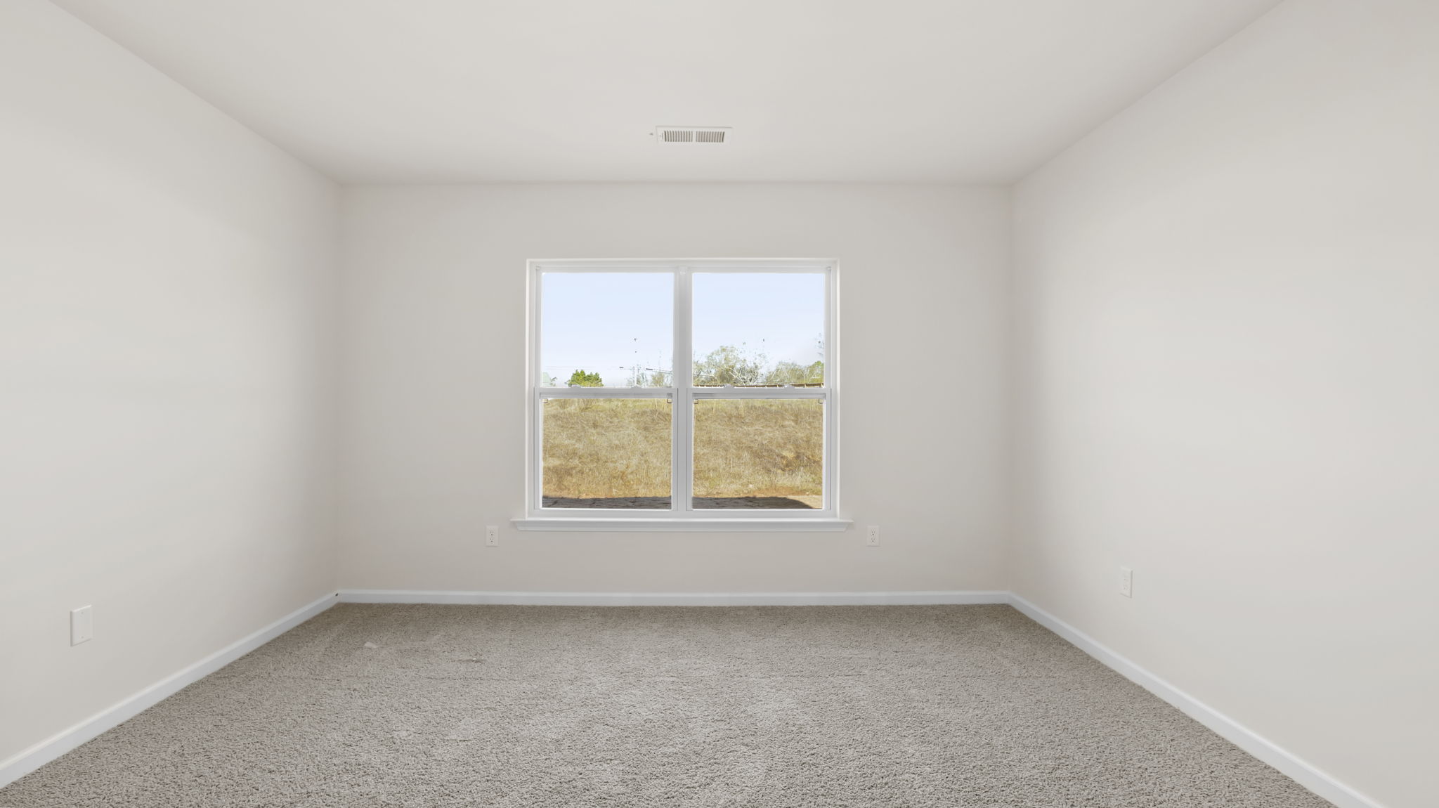 Primary bedroom with carpet and window.