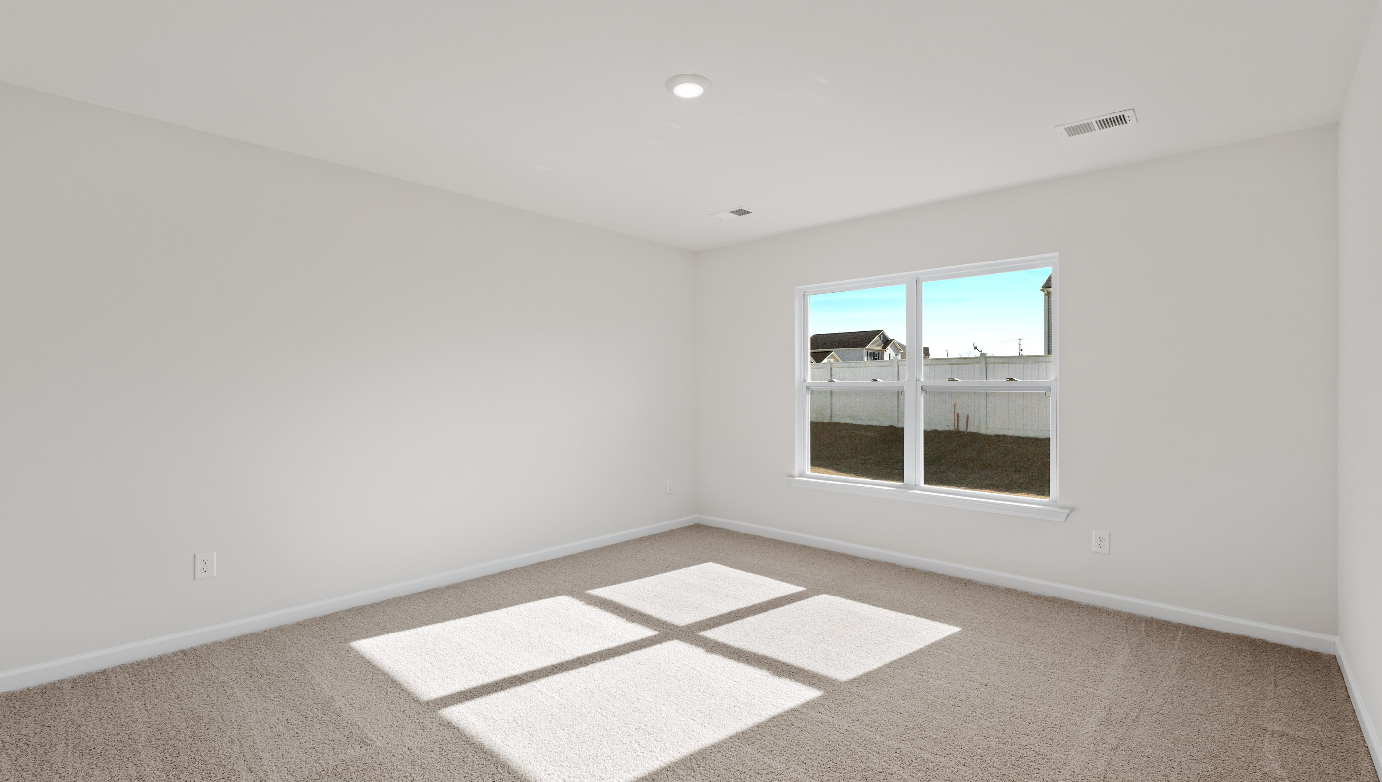 Primary bedroom with large window and carpet.