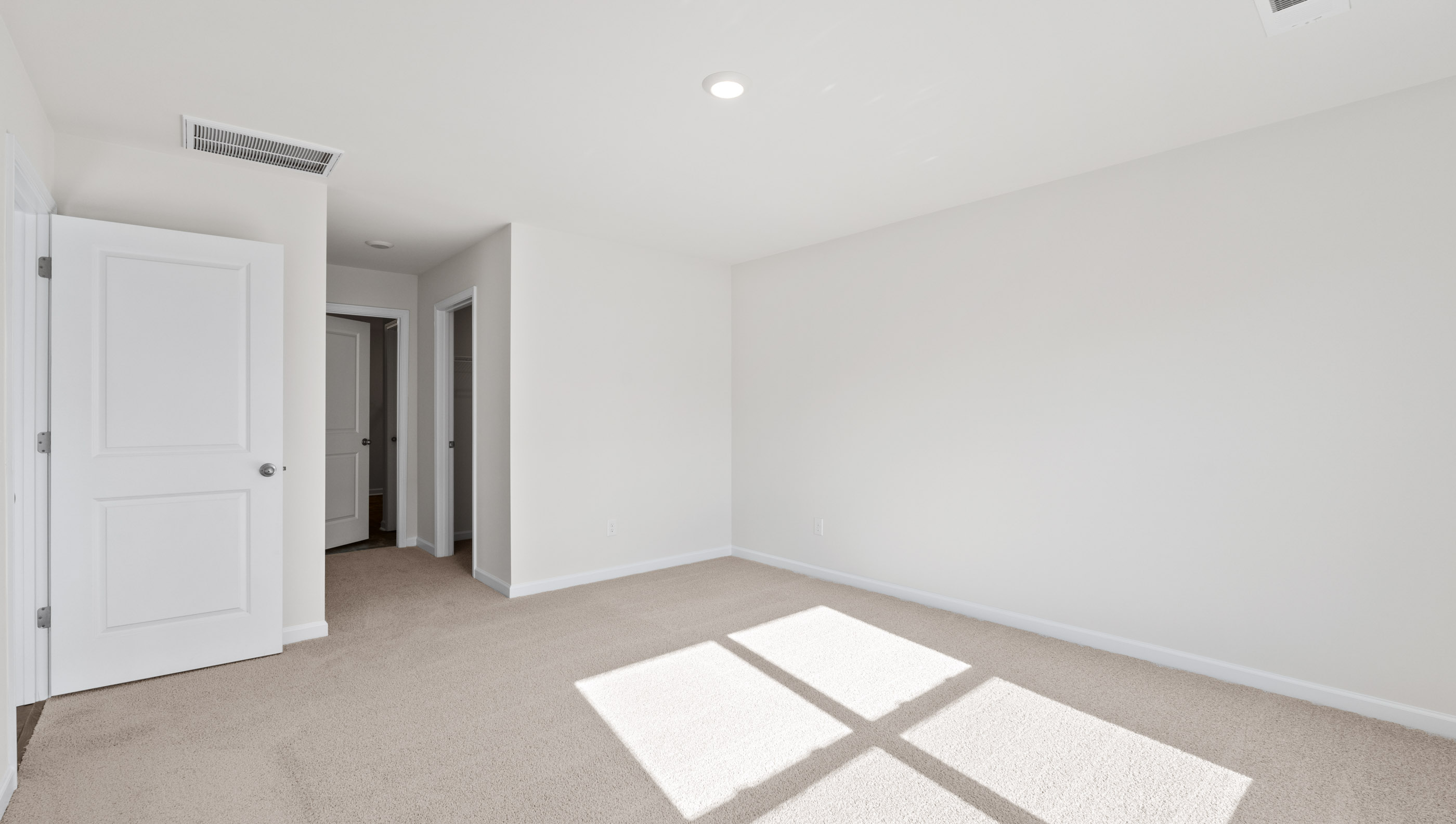 Primary bedroom with large window and carpet.