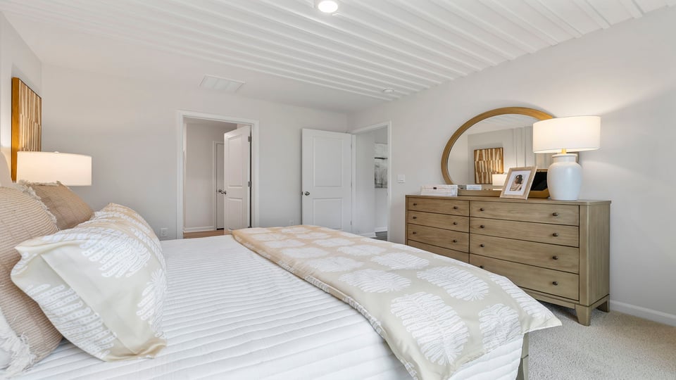 Primary bedroom with carpet and windows.