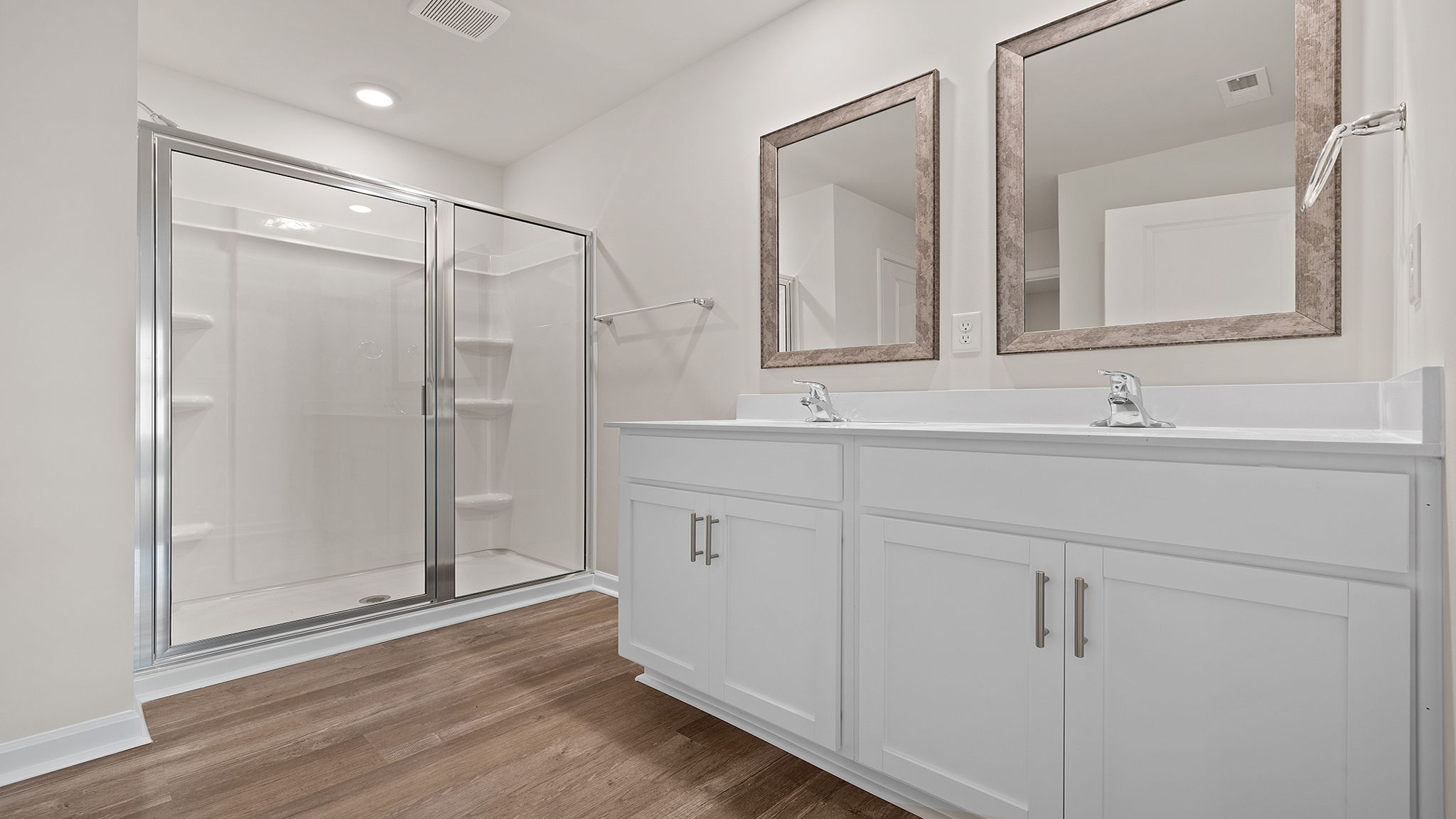 Primary bathroom with dual sink vanity and mirrors.