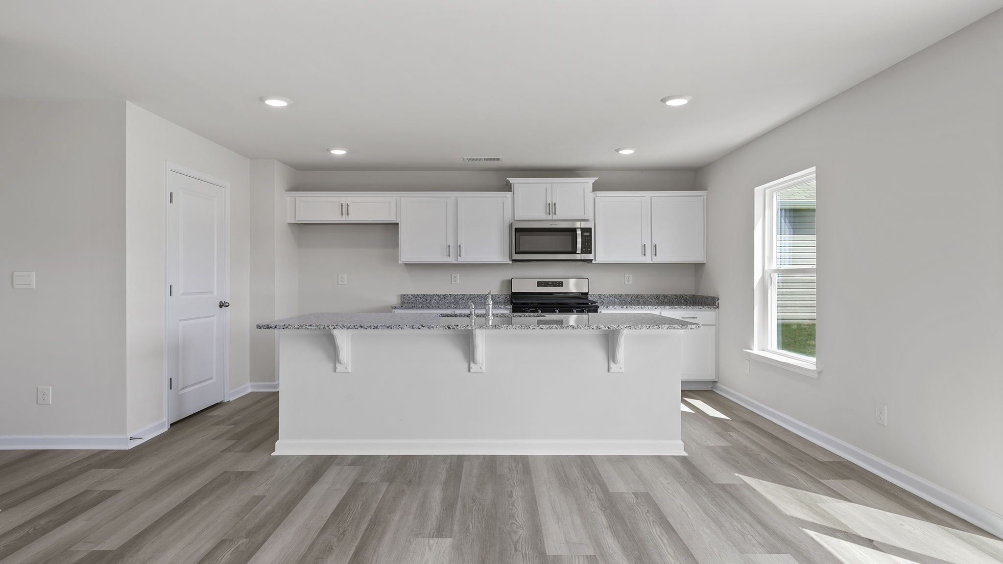 Kitchen area with granite island and stainless-steel appliances.
